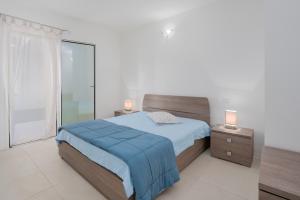 a bedroom with a bed with blue sheets and a window at Cormorani - Appartamento 3 in Golfo Aranci