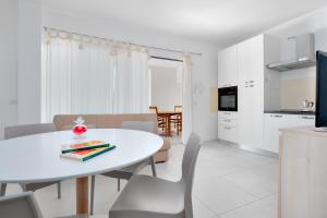 a white dining room with a white table and chairs at Cormorani - Appartamento 3 in Golfo Aranci
