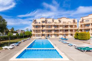 a hotel with a swimming pool and chairs and a building at Apartamento Espiga in Cala Bona