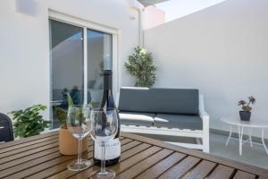 a bottle of wine and two wine glasses on a wooden table at Sunset Apartment in Sagres