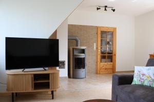 a living room with a flat screen tv on a wooden stand at Kleines Haus am Feld in Rehna +21 photos
