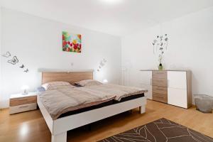a white bedroom with a bed and a dresser at Ferienwohnung Rheinvorland in Linx