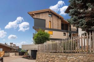 a house with a wooden fence in front of it at Aumia Apartment Opal in Völs am Schlern
