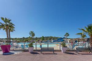 a pool at a resort with benches and palm trees at Le Mediterranéen in Fréjus