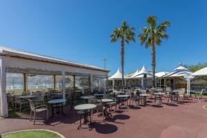 a patio with tables and chairs and palm trees at Le Mediterranéen in Fréjus