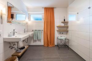 a bathroom with two sinks and an orange shower curtain at Die Ferienwohnung in Bad Bellingen +28 photos