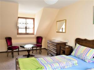a bedroom with a bed and a desk and chairs at Schmiede Burkheim in Vogtsburg