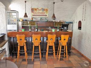 a bar with four orange bar stools in a restaurant at Schmiede Burkheim in Vogtsburg +24 photos