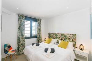 two beds in a bedroom with white walls and yellow pillows at Luxury apartment in Cómpeta +8 photos