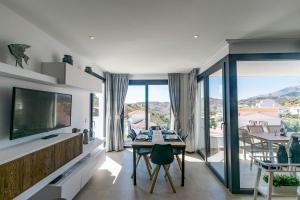 a living room with a television and a table with chairs at Luxury apartment in Cómpeta