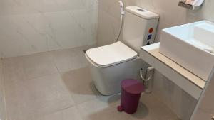 a white bathroom with a toilet and a sink at Joy Land Resort in Habarana