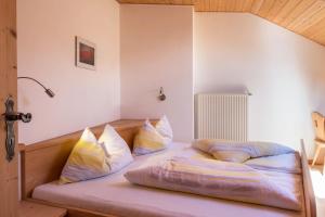 a bed with pillows on it in a room at Gamperhof Apartment Latemar in Collepietra