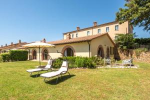 two chairs and an umbrella in front of a building at Villa Falco in Trequanda