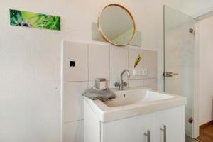 a white bathroom with a sink and a mirror at Ferienwohnung Griaß di in Salgen +16 photos