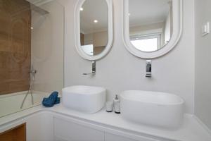 a bathroom with a white sink and two mirrors at Casa do Marquês in Vila Real de Santo António +20 photos
