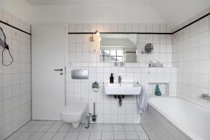 a bathroom with a sink and a toilet and a tub at Ferienwohnung Ackerkoog in Niebüll +16 photos
