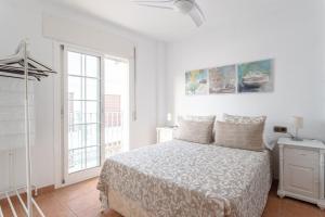 a white bedroom with a bed and a window at Apartamento San Juan 18 in Nerja