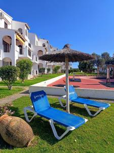 two chairs and an umbrella and a table and a pool at Magda - Cala En Porter in Cala en Porter