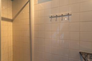 a shower in a bathroom with white tiles at La maison de vacances Mathieu in Artigues +14 photos