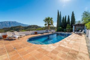 a swimming pool in a patio with chairs and a house at Bravo spectacular views in Viñuela
