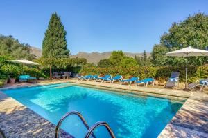 a swimming pool with chairs and umbrellas at Ca les Estamenyes in Pollença