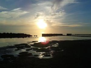 a sunset over a body of water with a pier at Ferienwohnungen Hiddenseeblick 3 in Dranske +2 photos