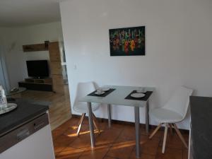 a small table in a kitchen with white chairs at Ferienwohnung Schneckenhaus in Ofterdingen +13 photos