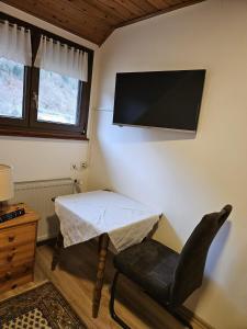 a room with a table and a tv on the wall at Am Wehrastrand Einzelappartment in Todtmoos
