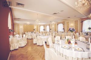um salão de banquetes com mesas brancas e cadeiras brancas em Pałac Pawłowice em Gorz