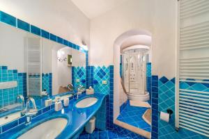 a blue tiled bathroom with two sinks and a toilet at Villa Lumaca in Porto Rotondo +24 photos