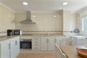 a kitchen with white cabinets and a sink and a table at Céntrico apartamento en Tarifa in Tarifa