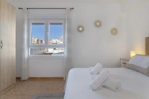 a white bedroom with a white bed and a window at Céntrico apartamento en Tarifa in Tarifa