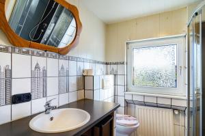 a bathroom with a sink and a toilet and a mirror at Ferienwohnung Klee 2 in Fedderwarden +13 photos