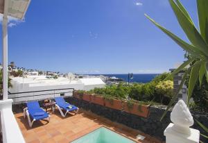 a patio with two blue chairs and a swimming pool at Villa Benedicte in Puerto del Carmen