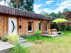 a wooden house with a table and an umbrella at Bungalow 314 in Joachimsthal