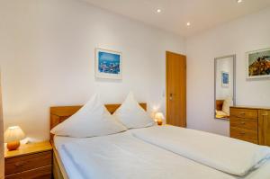 a bedroom with a white bed with white pillows at Haus Nussbaum in Hödingen
