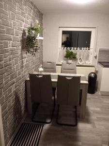 a dining room table with chairs and a brick wall at Ferienwohnung Conrads in Zetel