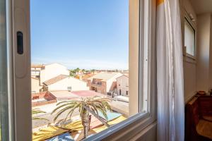 a view of a palm tree from a window at Grand Hotel Studio in Valras-Plage