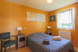 a bedroom with orange walls and a bed and a chair at Gîte Proche Mer 800 m in Plouézec