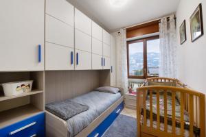 a bedroom with a crib and white cabinets and a window at Casa Vacanze Gianluca in Aosta