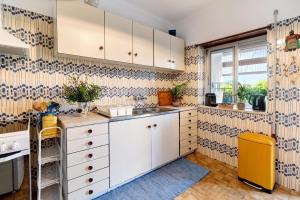 a kitchen with white cabinets and blue and white wallpaper at Retro Beach House Moledo in Moledo +29 photos