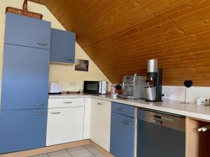 a kitchen with white cabinets and blue appliances at Ferienwohnung Heilsbronn in Heilsbronn