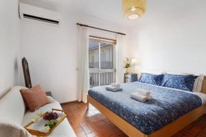 a bedroom with a bed and a couch and a window at Retro Beach House Moledo in Moledo