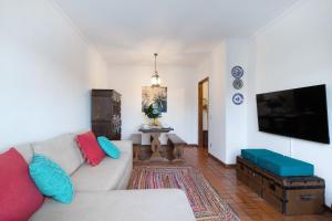 a living room with a couch and a flat screen tv at Retro Beach House Moledo in Moledo