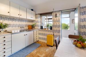 a kitchen with white cabinets and a table with a bowl of fruit at Retro Beach House Moledo in Moledo