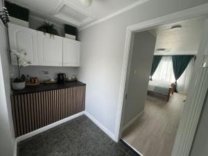 a kitchen with white cabinets and a hallway with a bedroom at Private Entrance En-suite in Gorey