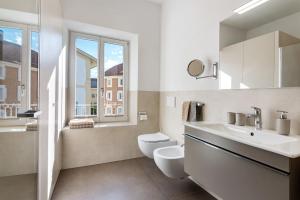 a white bathroom with a toilet and a sink at Sommavilla Apartments in Silandro