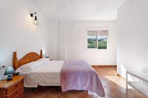 a white bedroom with a bed and a window at La Cuadra de Juan in Frontera