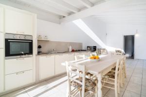 a white kitchen with a white table and chairs at Domo Bonaeras in Irgoli +19 photos