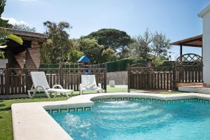 a swimming pool in a yard with two chairs and a fence at Villa Africa in La Muela